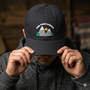 May include: A black baseball cap with the text "find your summit" embroidered above a mountain and sun graphic. The cap has a curved brim and is made of a durable fabric. The design is in white, green, and yellow.