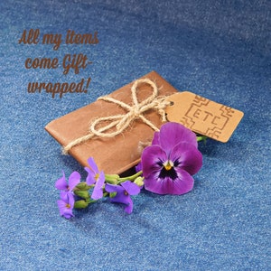 Gift wrapped item in brown tissue paper with hemp string and and hand stamped gift tag with ETC logo. On a blue denim background with Pansy & Aubretia Flowers. With the words All my Items come Gift Wrapped!