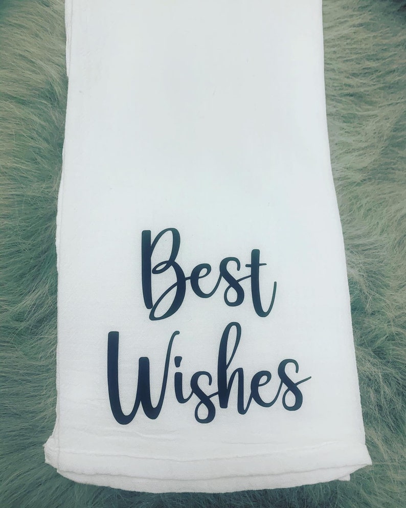 May include: White kitchen towel with black cursive text that reads "Best Wishes".