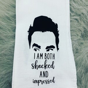 May include: A white kitchen towel with a black silhouette of a man's face and the text "I am both shocked and impressed".