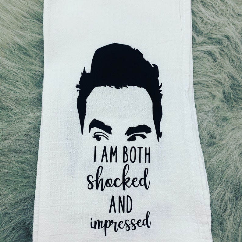 May include: A white kitchen towel with a black silhouette of a man's face and the text "I am both shocked and impressed".