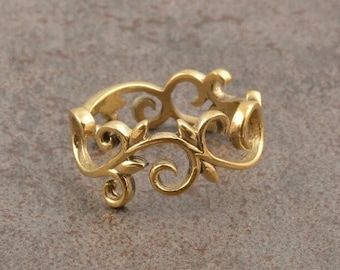 May include: A gold-toned metal ring featuring an openwork design composed of interconnected swirling vine and leaf motifs. The band has a continuous, repeating pattern of curved lines and pointed leaf shapes throughout its circumference.