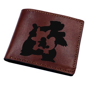 May include: A brown leather wallet with a black silhouette of three Pokemon characters. The characters are Snorlax, Eevee, and Flareon.