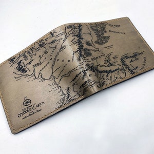 May include: A brown leather wallet with a map of Middle-earth printed on the front. The map includes the text "The Realms of Middle-earth".