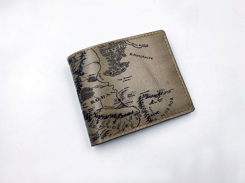 May include: A brown leather wallet with a black and white map of Middle-earth printed on the front. The map includes the names "Rohan", "Mordor", and "Rhovanion".
