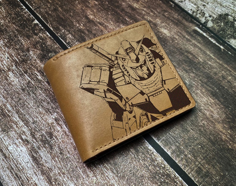 May include: A brown leather wallet with a laser-engraved design of a robot. The robot is in a detailed, stylized design with a large head and a weapon.