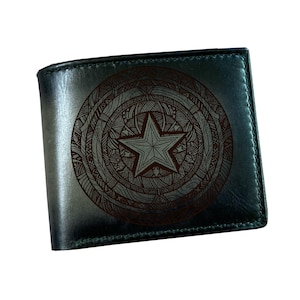 May include: A dark teal leather wallet featuring a detailed star and circular design. The star is centrally placed within an intricate pattern, creating a unique and stylish accessory. The wallet is rectangular and appears to be new.