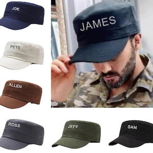 May include: Six different coloured baseball caps with various names embroidered on the front. The caps are all the same style, with a flat top and a curved brim. The names on the caps are "JOE", "PETE", "ALLEN", "ROSS", "JEFF", and "SAM".