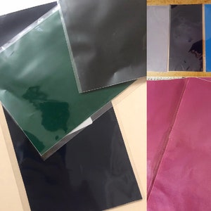 May include: A set of four different colored sheets of paper, each with a clear plastic sleeve. The colors are green, black, gray, and pink.