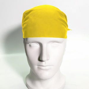 May include: A bright yellow bandana made of fabric. The bandana is tied around the head of a white mannequin.
