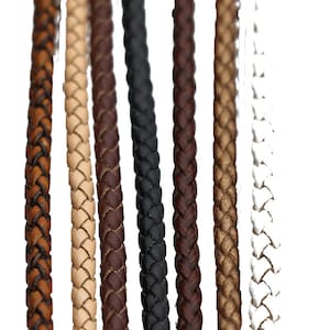 Op de afbeelding: Zeven strengen gevlochten lederkoord in verschillende kleuren, waaronder bruin, beige, zwart en wit.