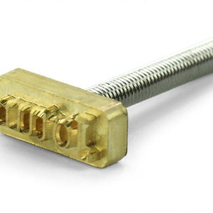 May include: A brass stamping tool with a threaded metal handle. The stamping head has the letters "1000" embossed on it.