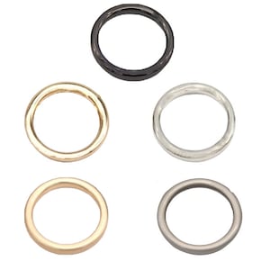 May include: Six metal rings in different finishes: black, gold, silver, and two shades of gray. The rings are all the same size and shape, and they are arranged in a symmetrical pattern.