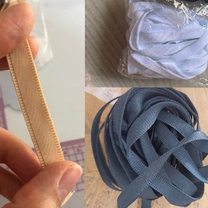 May include: Three spools of elastic ribbon. One spool is beige, one is white, and one is dark blue.