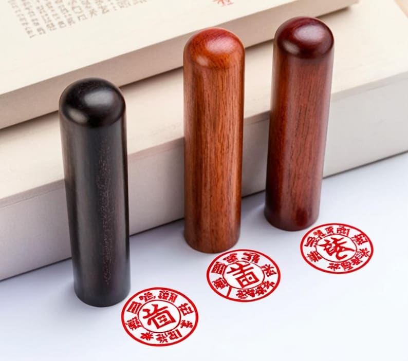 Peut inclure: Trois tampons en bois avec des impressions d'encre rouge. Les tampons sont cylindriques et ont un sommet arrondi. Les impressions d'encre sont circulaires et contiennent des caract&egrave;res chinois.