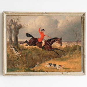 Puede incluir: Una pintura de un hombre a caballo cabalgando por un campo con tres perros corriendo detrás de él. El hombre lleva un abrigo rojo y un sombrero negro. El caballo es marrón y blanco. Los perros son marrones y blancos.