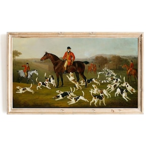 Op de afbeelding: Een schilderij dat een groep mensen te paard toont, met een man in een rode jas die de leiding heeft. De groep wordt omringd door een roedel honden, waarvan sommige in de lucht springen. De scène speelt zich af in een landelijk landschap met bomen en velden.