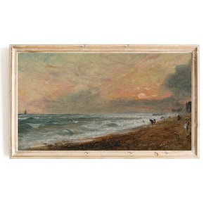May include: A framed oil painting depicting a seascape with a stormy sea, a sandy beach, and a group of people walking along the shore. The sky is a mix of gray and pink, with a bright orange sun setting in the distance.