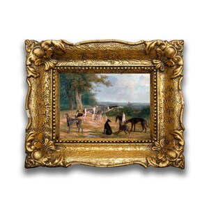 May include: A framed oil painting depicting a group of greyhounds in a wooded landscape. The dogs are standing and sitting in a clearing, with a small figure in the background. The painting is set in a gold frame with ornate details.