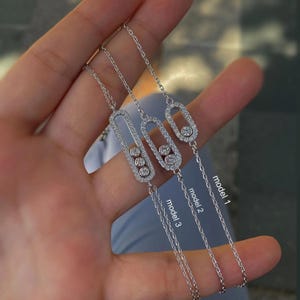 May include: Three silver bracelets with a delicate chain design. Each bracelet features a rectangular or oval-shaped pendant encrusted with small, sparkling crystals. The bracelets are labelled "model 1", "model 2", and "model 3".
