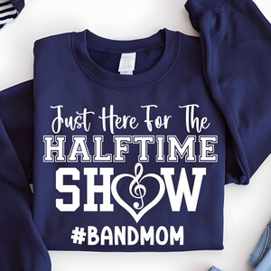 May include: Navy blue sweatshirt with the text "Just Here For The Halftime Show" in white. The word "SHOW" is inside a heart with a treble clef. Below the heart is the hashtag "#BANDMOM".