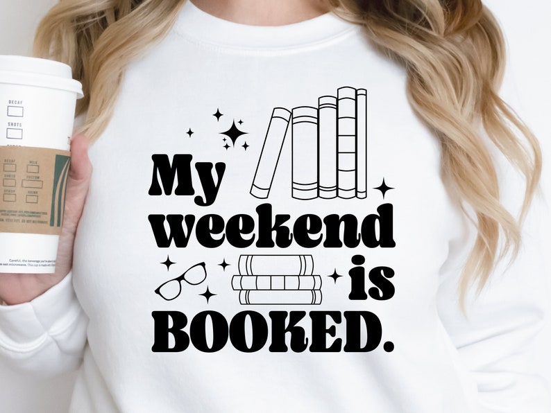 May include: White sweatshirt with black text that reads "My weekend is BOOKED."  The text is in a retro font.  There are illustrations of books and glasses.