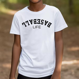 May include: White t-shirt with black text that reads "BASEBALL LIFE" in an arched font.