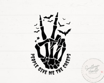Può includere: Grafica nera con una mano di scheletro che fa il segno della pace, circondata da pipistrelli e stelle. Il testo "PEOPLE GIVE ME THE CREEPS" è sotto. Tema Halloween.