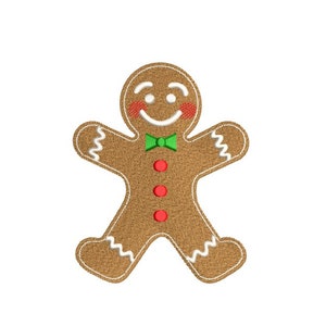 Könnte beinhalten: Ein Lebkuchenmann mit grüner Schleife und roten Knöpfen. Der Lebkuchenmann hat ein lächelndes Gesicht mit weißem Zuckerguss und roten Wangen.