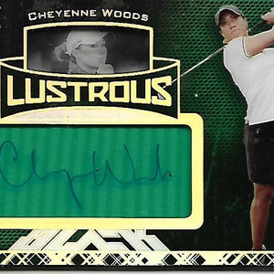 Puede incluir: Una tarjeta de intercambio deportivo verde y dorada con una foto de una mujer con una camisa blanca y una falda negra balanceando un palo de golf. La tarjeta tiene el texto "Cheyenne Woods" y "Lustrous" en ella. La tarjeta está numerada "101/135" y tiene un parche de firma verde con el texto "Cheyenne Woods" en ella.