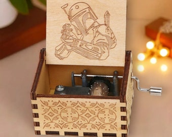 May include: A wooden music box with a laser-etched image of a character from a science fiction film. The box features a decorative floral pattern on the front and a hand crank on the side. The lid is open, revealing the internal mechanism.