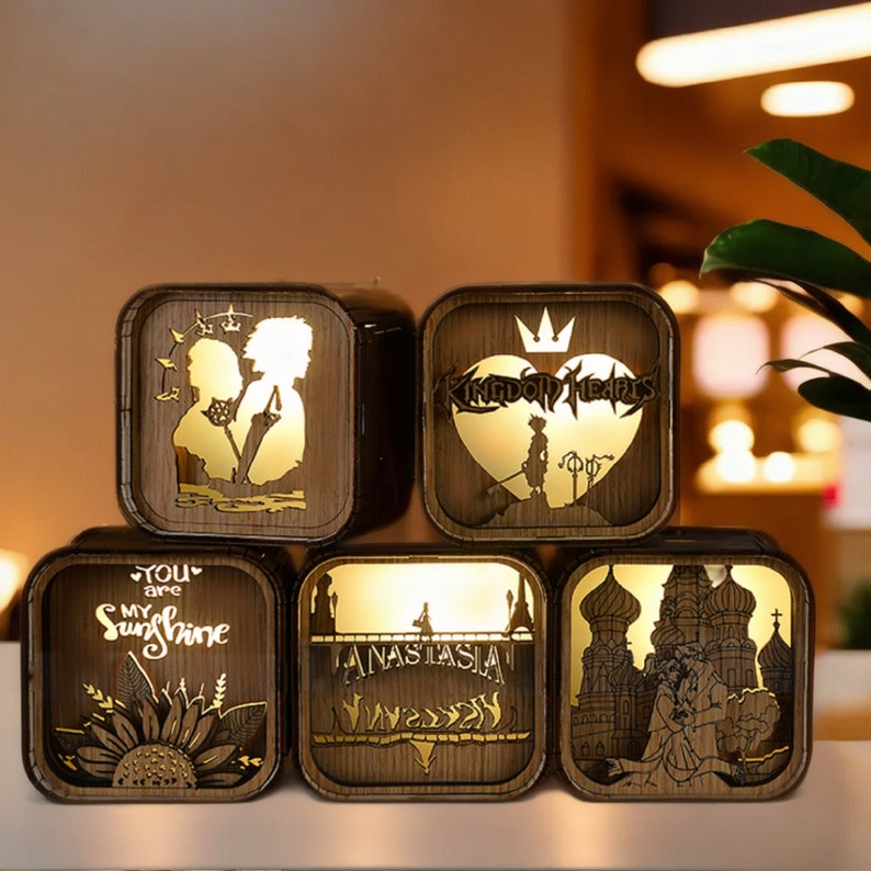 May include: Five wooden, square-shaped decorative lamps with illuminated designs. The lamps feature various cut-out silhouettes and text, including a sunflower, a couple, and the words "You are my Sunshine" and "Anastasia".