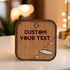 May include: Wooden music box with the text "CUSTOM YOUR TEXT" and an arrow pointing down. The box has a light brown wood grain finish, a Sankyo music mechanism, and decorative silver accents.