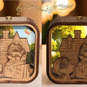 May include: Wooden light box featuring a laser-cut design of a couple kissing in front of a house, with the text "Love You" on a book. The box has a warm, inviting glow, and the design is reminiscent of a classic animated film.