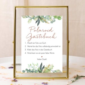Peut inclure: Une pancarte blanche avec une bordure de feuillage vert dans un cadre dor&eacute;. La pancarte indique "Polaroid G&auml;stebuch" et contient des instructions pour un livre d'or Polaroid : 1. Prenez une photo de vous-m&ecirc;mes, 2. Attendez que la photo soit enti&egrave;rement d&eacute;velopp&eacute;e, 3. Collez la photo dans le livre d'or, 4. Laissez-nous quelques mots d'amour.  Vielen Dank!"
