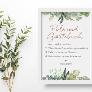 Peut inclure: Une affiche encadr&eacute;e blanche avec une bordure florale verte et le texte "Polaroid G&auml;stebuch" en lettres brunes. L'affiche comprend des instructions pour que les invit&eacute;s prennent une photo Polaroid, attendent qu'elle se d&eacute;veloppe, la collent dans le livre d'or et laissent un message. L'affiche se termine par "Vielen Dank!"