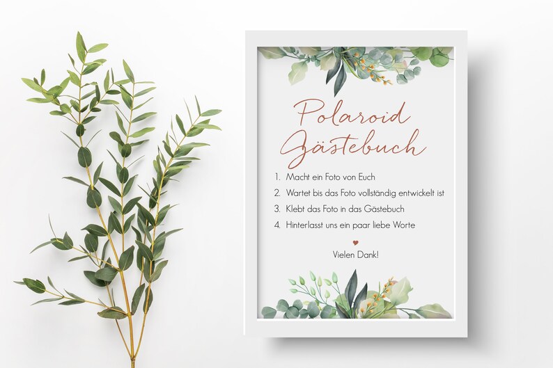 Peut inclure: Une affiche encadr&eacute;e blanche avec une bordure florale verte et le texte "Polaroid G&auml;stebuch" en lettres brunes. L'affiche comprend des instructions pour que les invit&eacute;s prennent une photo Polaroid, attendent qu'elle se d&eacute;veloppe, la collent dans le livre d'or et laissent un message. L'affiche se termine par "Vielen Dank!"