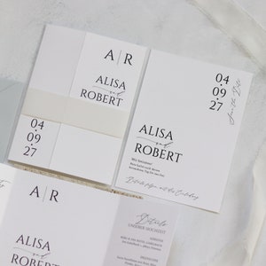 May include: A white wedding invitation with black text. The invitation reads "ALISA and ROBERT" with the date "04.09.27" and the text "Save the Date".