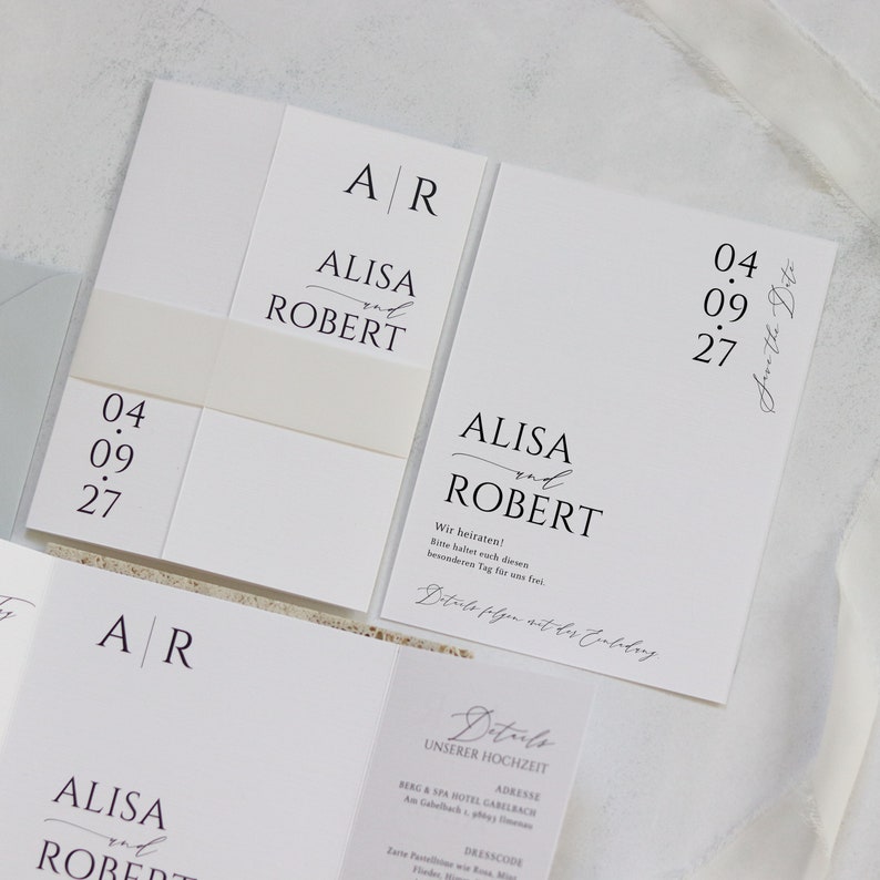 May include: A white wedding invitation with black text. The invitation reads "ALISA and ROBERT" with the date "04.09.27" and the text "Save the Date".