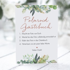 Peut inclure: Une carte blanche avec un feuillage vert et un texte brun superpos&eacute; qui dit "Polaroid G&auml;stebuch". La carte contient des instructions pour que les invit&eacute;s prennent une photo Polaroid, attendent qu'elle se d&eacute;veloppe, la collent dans le livre d'or et laissent un message. Le texte dit &eacute;galement "Vielen Dank!"