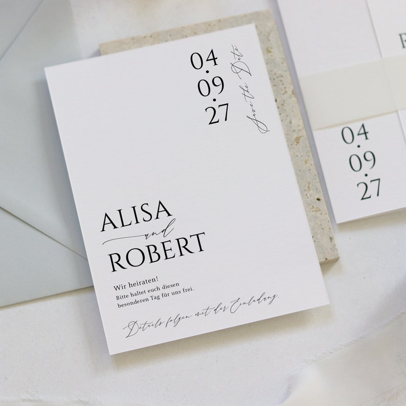 May include: A white wedding invitation with black text. The invitation reads "ALISA and ROBERT" with the date "04.09.27" and the text "Save the Date".