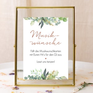 May include: A gold-framed sign with a white background and green foliage illustrations. The text reads "Musik-w&uuml;nsche" and "F&uuml;llt die Musikwunschkarten mit Euren Hit's f&uuml;r den DJ aus. Lasst uns tanzen!"