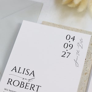 May include: A white wedding invitation with black text. The invitation reads "ALISA and ROBERT" and "Save the Date 04.09.27".