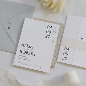 May include: A white wedding invitation with black text. The invitation reads "ALISA and ROBERT" with the date "04.09.27" and the text "Save the Date".