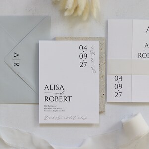 May include: A white wedding invitation with black text. The invitation reads "ALISA and ROBERT" with the date "04.09.27" and the text "Save the Date".