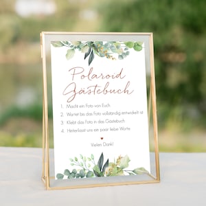 Peut inclure: Une pancarte blanche avec un cadre dor&eacute; et des accents floraux verts. La pancarte indique "Polaroid G&auml;stebuch" et comprend des instructions pour que les invit&eacute;s prennent une photo, attendent qu'elle se d&eacute;veloppe, puis la collent dans le livre d'or. La pancarte indique &eacute;galement "Vielen Dank !"
