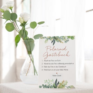 Peut inclure: Une carte blanche avec une bordure de feuillage vert et le texte "Polaroid G&auml;stebuch" en &eacute;criture cursive brune. La carte &eacute;num&egrave;re les instructions pour un livre d'or Polaroid&nbsp;: 1. Prenez une photo de vous, 2. Attendez que la photo soit enti&egrave;rement d&eacute;velopp&eacute;e, 3. Collez la photo dans le livre d'or, 4. Laissez-nous quelques mots d'amour.  Vielen Dank! (Merci beaucoup&nbsp;!)