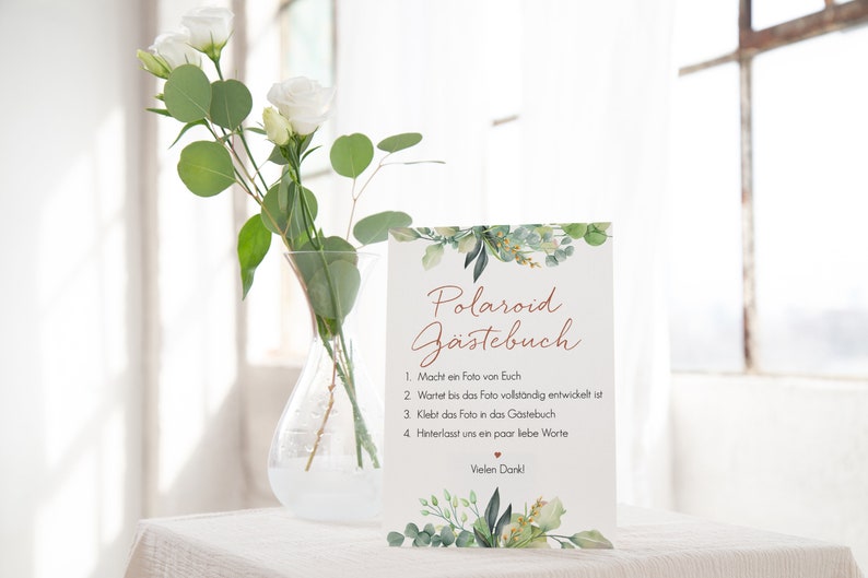 Peut inclure: Une carte blanche avec une bordure de feuillage vert et le texte "Polaroid G&auml;stebuch" en &eacute;criture cursive brune. La carte &eacute;num&egrave;re les instructions pour un livre d'or Polaroid&nbsp;: 1. Prenez une photo de vous, 2. Attendez que la photo soit enti&egrave;rement d&eacute;velopp&eacute;e, 3. Collez la photo dans le livre d'or, 4. Laissez-nous quelques mots d'amour.  Vielen Dank! (Merci beaucoup&nbsp;!)