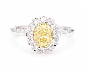 May include: A platinum ring featuring a large, oval-cut yellow diamond center stone, surrounded by a halo of smaller, round white diamonds. The ring has a classic, elegant design, perfect for engagement or special occasions.