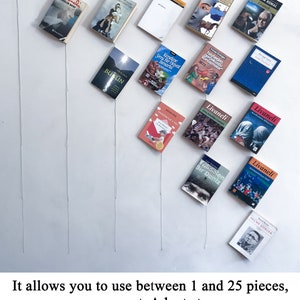 May include: An assortment of small books with colorful covers and various titles, arranged on a white wall. The books are suspended by thin strings, creating a unique display. The image includes text at the bottom.